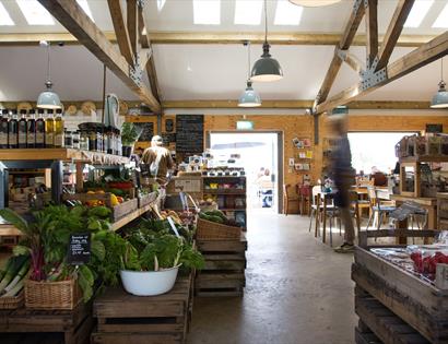 interior of farm shop with beams on ceiling and fresh salad leaves in foreground.