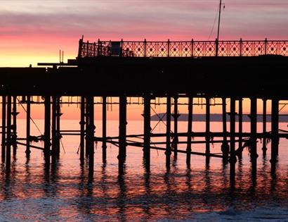silhouetted pier structure against the sunset.