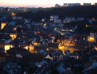 Twilight photograph of the town of Hastings. Looking down from the East Hill onto street lit houses.