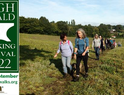 Poster for High Weald Walking Festival, group of walkers crossing a field.
