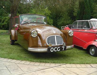 a vintage brown car parked on a lawn.