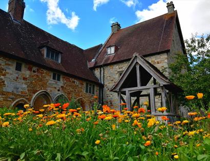photograph of a historic stone property from a low angle with field of marigolds in the foreground.