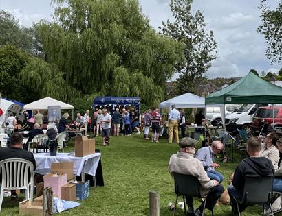 out event with small marquees on lawn and groups of people