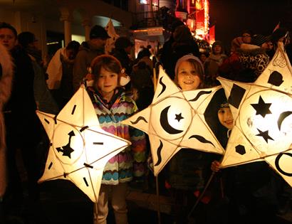 three children holding paper lanterns in the shape of stars