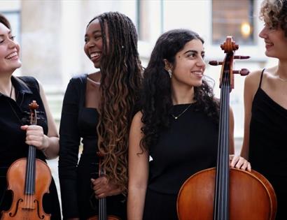 Four musicians in black attire holding string instruments, standing outdoors for a Spring Quartet concert.