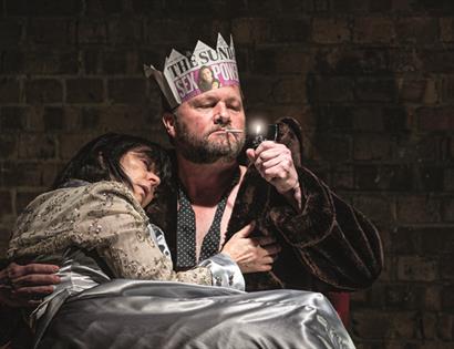 close up of stage performance. Man with paper crown holds lady in his arms
