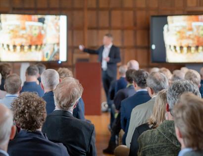 Audience watching a speaker present historic images during the Community Open Day at Herstmonceux Castle.