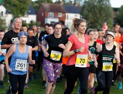 Group of runners wearing numbered bibs start a race for Nice Work.