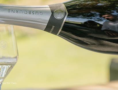 Bottle of Gusbourne sparkling wine being poured into two flutes