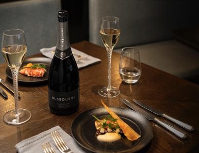 photograph of a dining table with food and bottle of Gusbourne sparkling wine