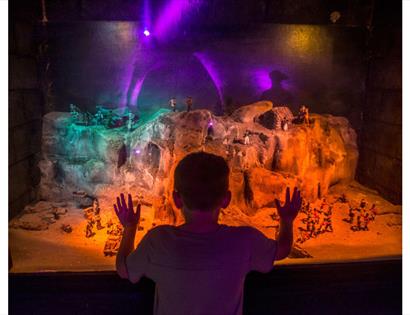 Child looking at a miniature model of smugglers using the caves, at Smugglers adventure Hastings