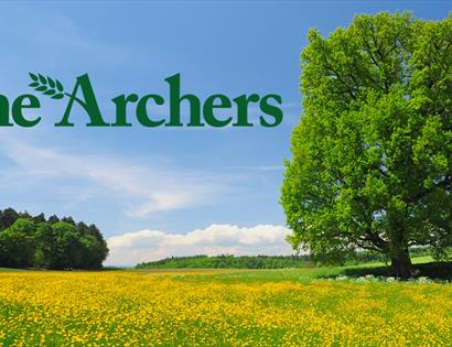 poster for the archers shows green text "The Archers" with yellow meadow and oak tree in the background.