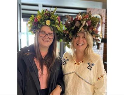 Image shows picture of 2 people wearing flower crowns at Jack in the Green