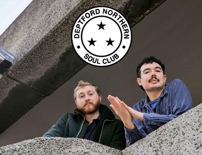Two people stand on a concrete balcony beneath a ‘Deptford Northern Soul Club’ logo.