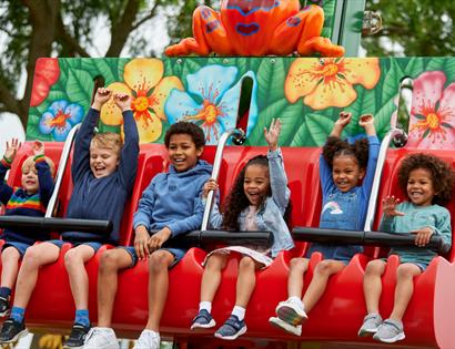 Children enjoying a colourful frog-themed drop ride at Drusillas Park