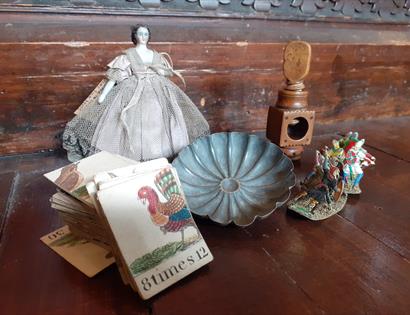 photograph of vintage toys placed together, including a porcelain doll and cards.