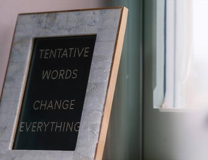 picture frame with text within stating 'tentative words change everything'.