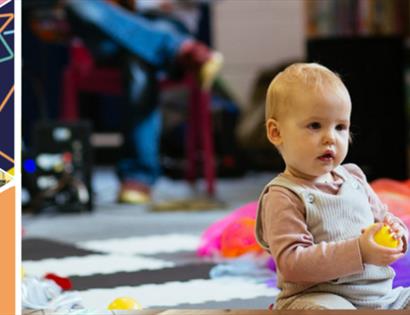 baby sat on the floor holding a yellow ball