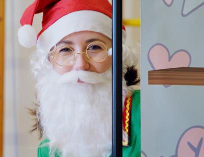 A Christmas elf wears a Santa beard