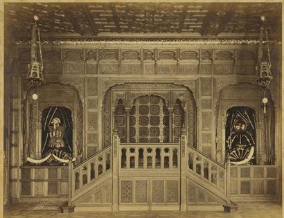 black and white photo of a carved hall with horns and armour on display