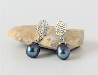 a photograph of earings placed on a small light coloured stone. Silver dangling earings with blue pearlescent stone.