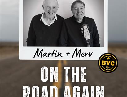 Poster with photograph of two white men, one with guitar, blurred background image of a road. Text reads "Martin & Merv on the road again".