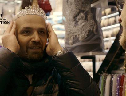 photograph of man in shop trying on a tiara.