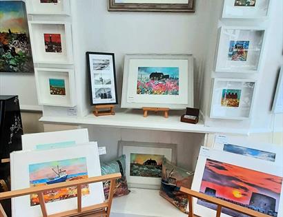 interior photograph of art gallery showing prints in cradle and in frames on white wall