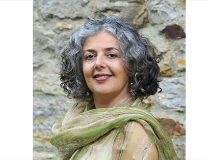 a photograph of a woman against an old brick wal, wears green silk shawl.