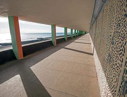 photograph of a roofed concrete promenade looking out to the sea.