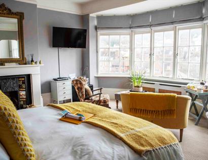 Bright yellow room at The Laindons with large windows overlooking Hastings rooftops and coastline.