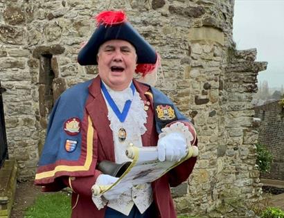 photograph of town crier in traditional costume reading from a scroll