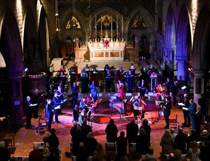 Singers of Hastings Philharmonic Orchestra on stage under coloured lights.