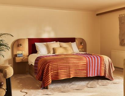 Image shows the inside of one of the bedrooms at Crafted at Powdermills. The Room is bright, light and neutral tones. The bed is in the centre of the