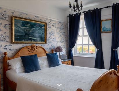 Image shows one of the rooms at The Hope Anchor Hotel. It has two big windows either side of the wall. The room is tastefully decorated in a neutral a
