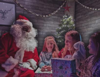 Festive gathering at Christmas: Santa sits to the left, facing three excited children near a twinkling tree. A patterned present is front and center,