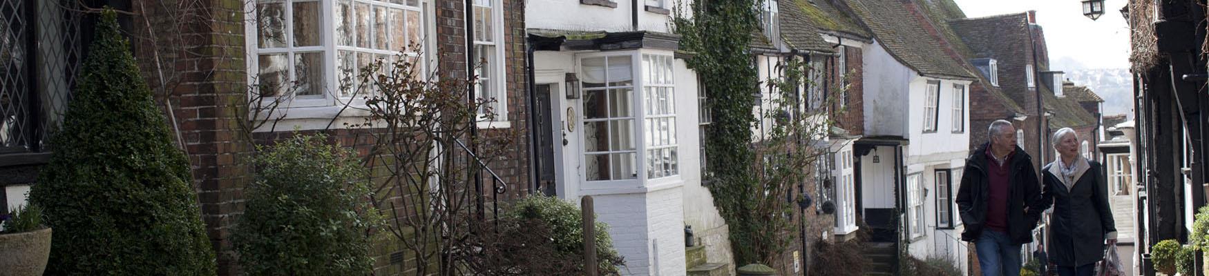 A couple walking up a street with buildings in rye