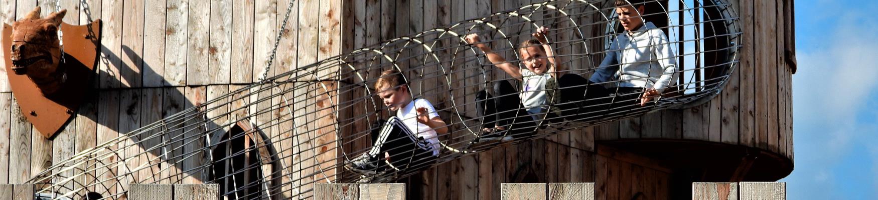 Children climbing through a metal tunnel at Knockhatch Adventure Park