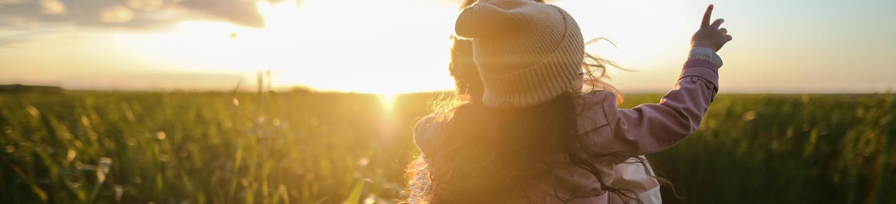 Mother and child in field at sunset