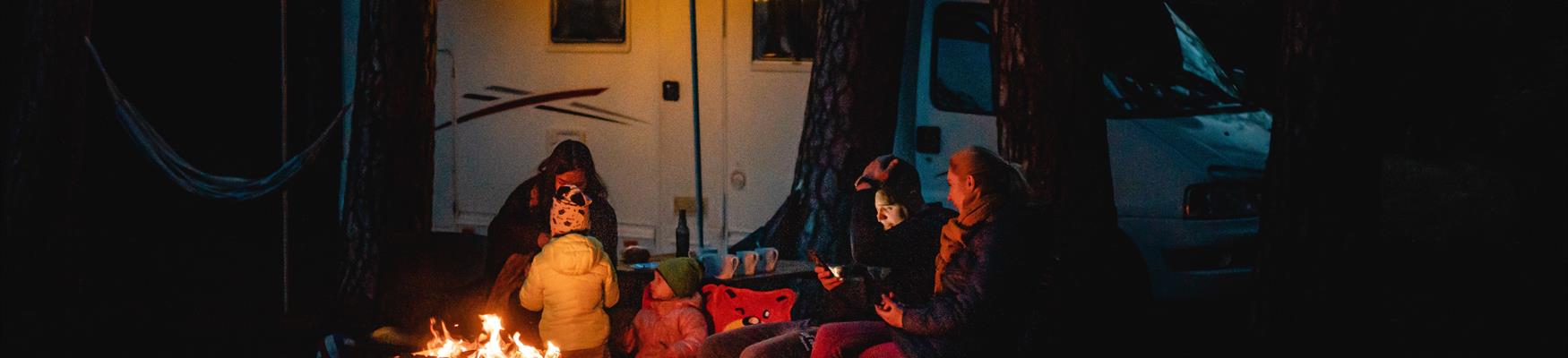 A family at night outside their camper van