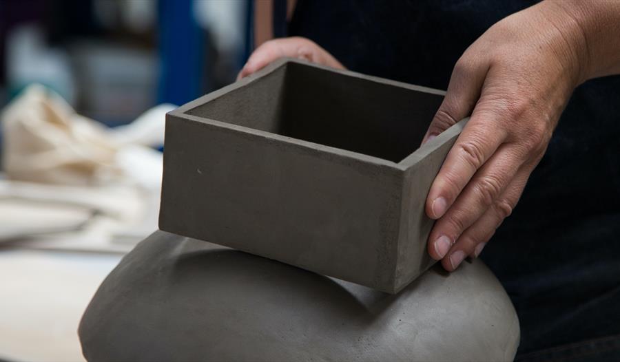 close up of potter's hands with clay box.