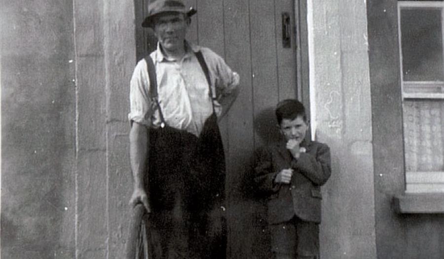 old black and white photograph of man and boy standing in doorway