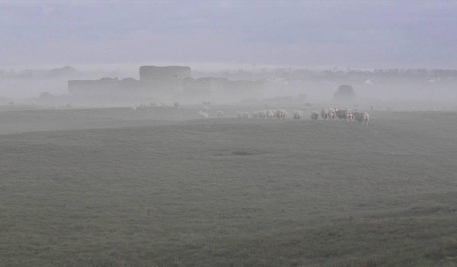 A picture of fields in mist with Camber Castle in the distance.