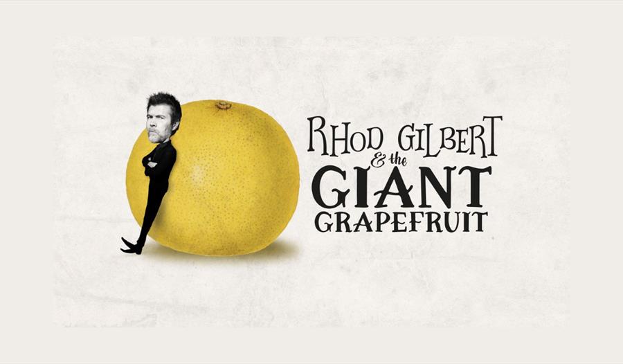 Rhod Gilbert leaning on a large grapefruit