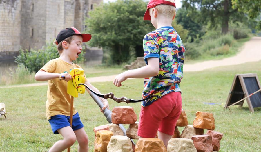 two young children with hobby horse and archery bow at Bodiam Castle.