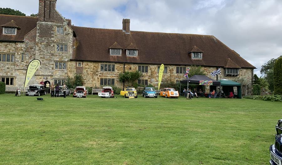 cars on a lawn in front of historic brick property.