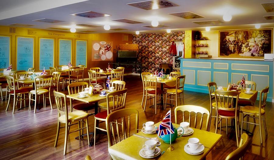 a photograph of the interior the British Tea Museum, Hastings, East Sussex. showing chairs and tables with cups and saucers, with union jack flags as
