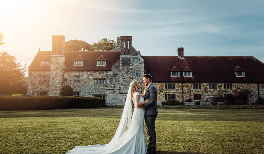 bride ang groom on lawn in front of an old brick building.
