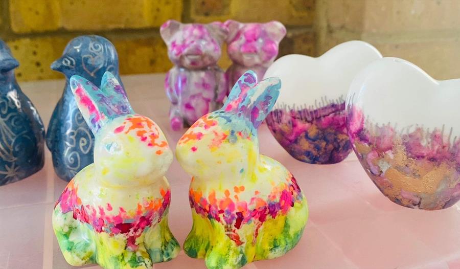 photograph of brightly painted ceramics in the shape of rabbits, penguins, bears and love hearts.