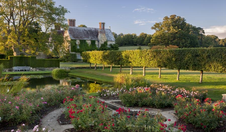 formal gardens with stone house in background.
